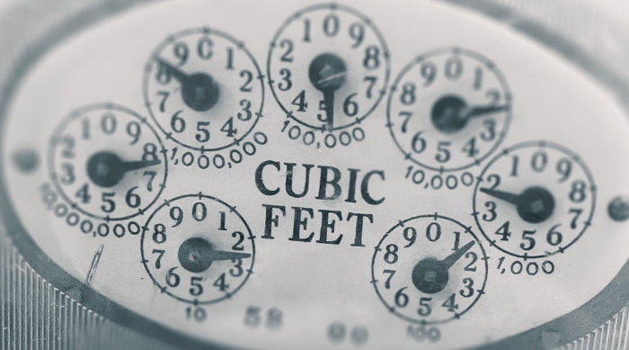 A close-up photograph of a dial meter showing cubic feet as the unit.