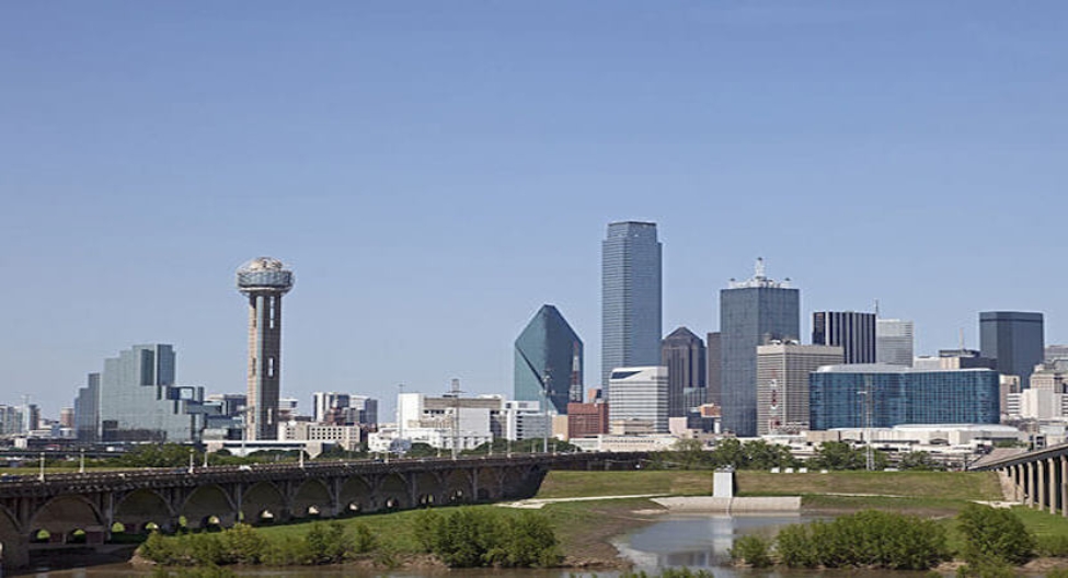 a city skyline of Dallas, Texas with a river and a bridge in the foreground