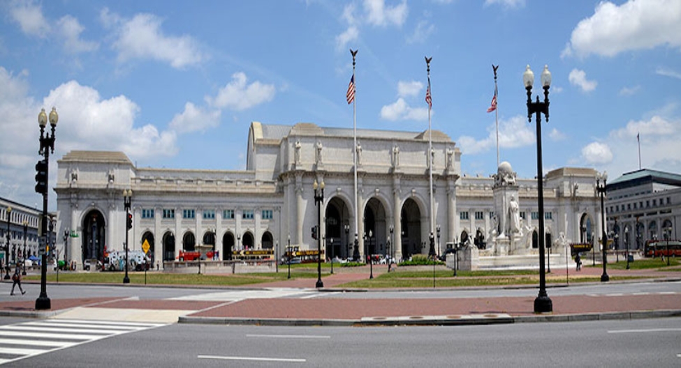 a large stone building with flags with Union Station in the background