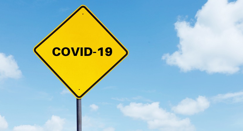 a yellow street sign with black text saying 'COVID-19'
