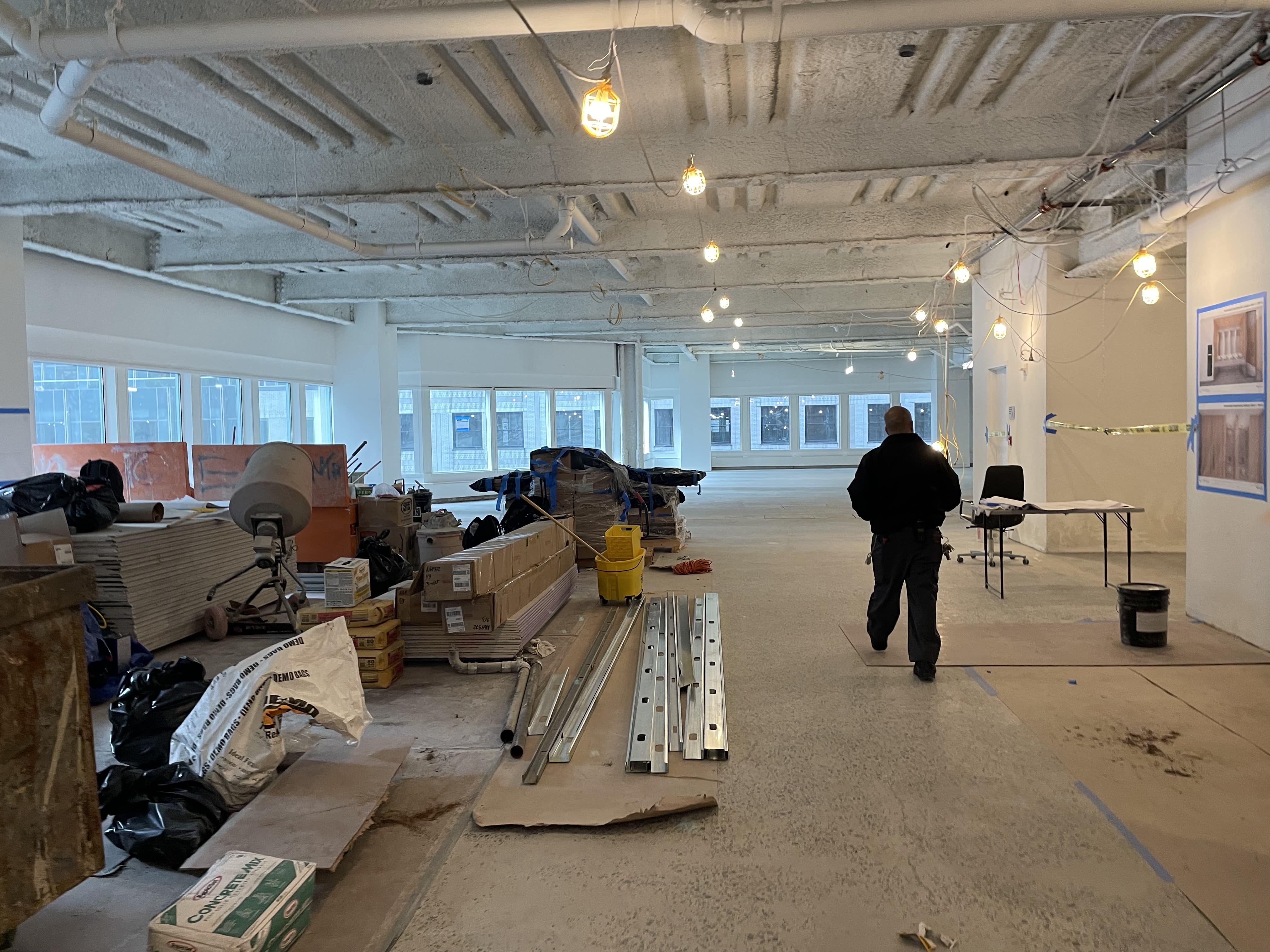 A worker walks through a job site, with large piles of supplies waiting to build out the floor.